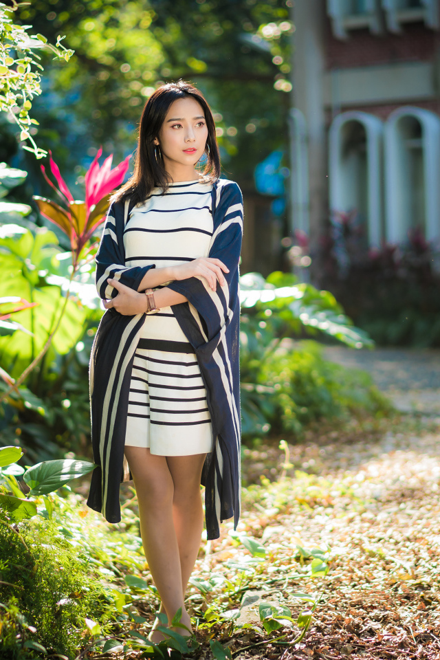 Девушка азиатка идет по улице у забора