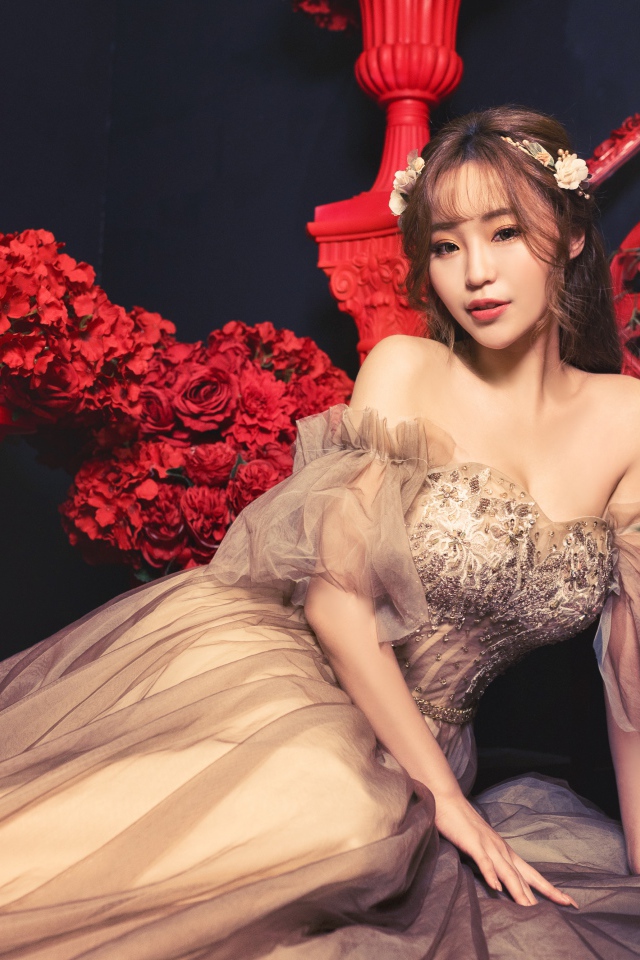 Азиатка в красивом платье в комнате с красными цветами