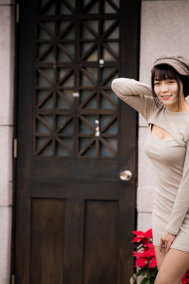 Красивая азиатка в платье стоит у двери 