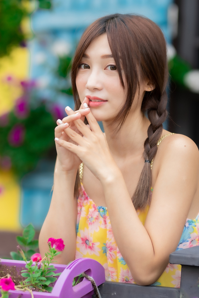 Красивая девушка Азиатка у цветов петунии