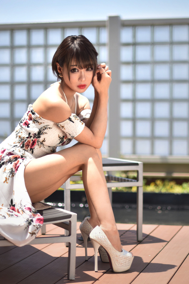 Красивая девушка азиатка сидит на шезлонге 