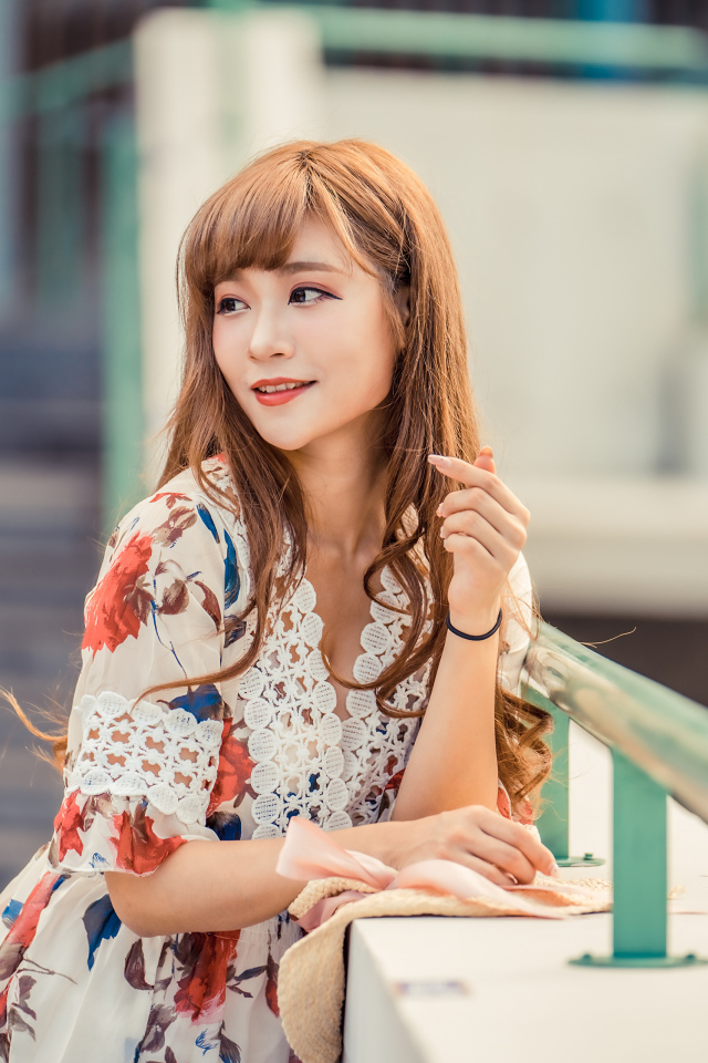 Красивая девушка азиатка стоит у перил 