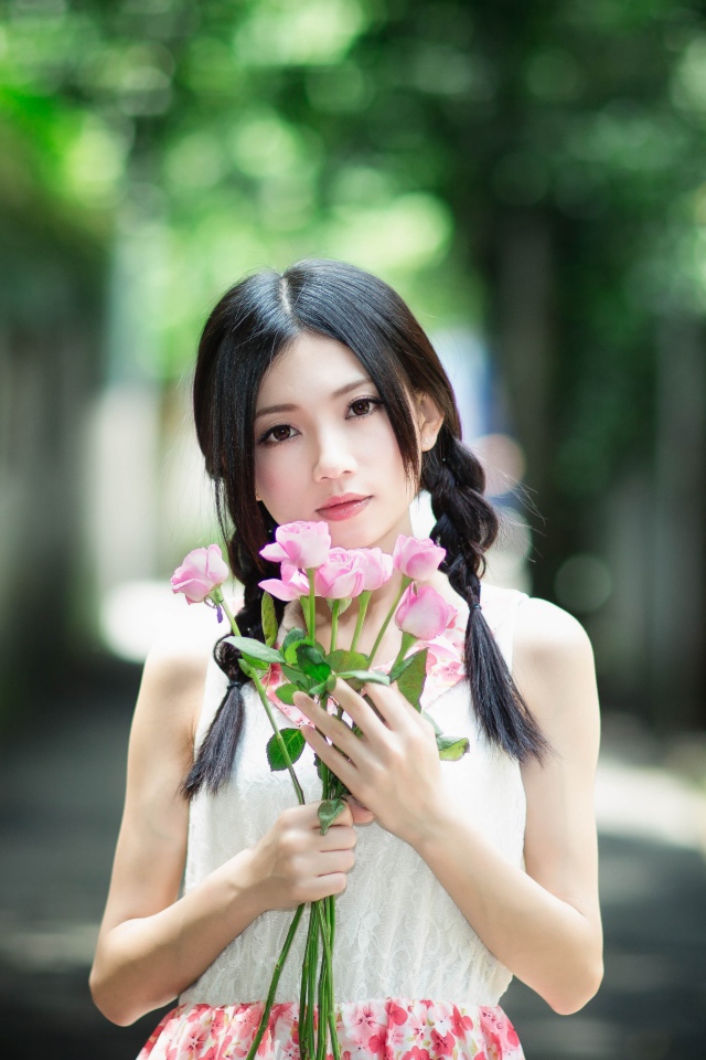 Красивая девушка азиатка в букетом роз в руках