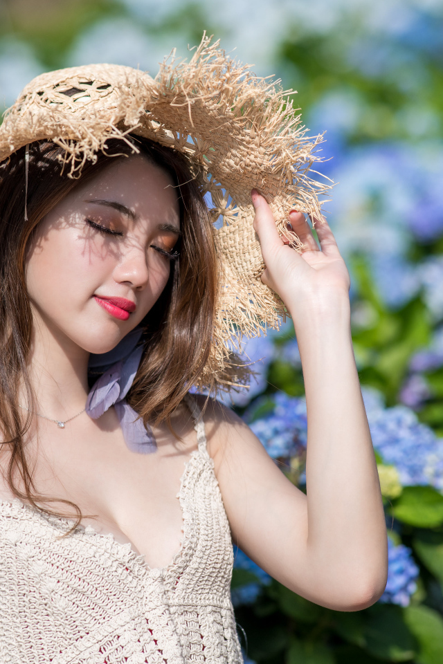 Красивая девушка азиатка с закрытыми глазами на фоне цветов гортензии