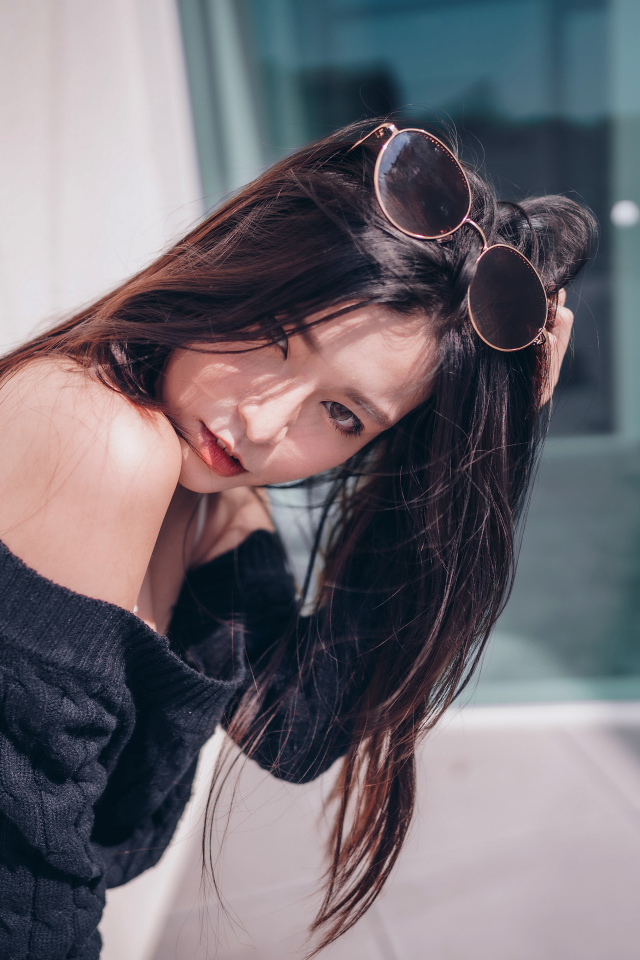 Красивая азиатка в черном свитере с солнечными очками на голове 