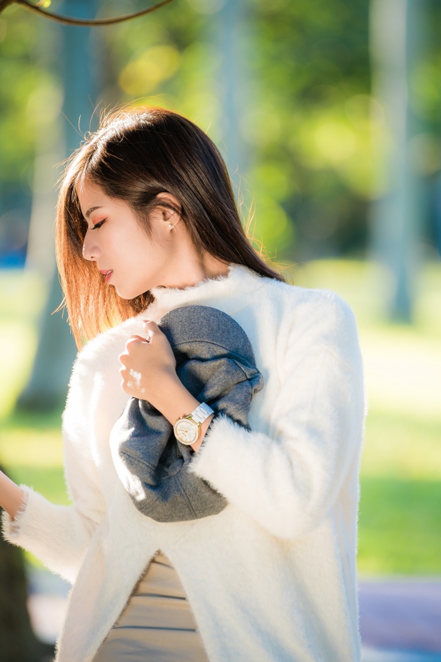 Красивая азиатка в белой кофте в солнечном парке