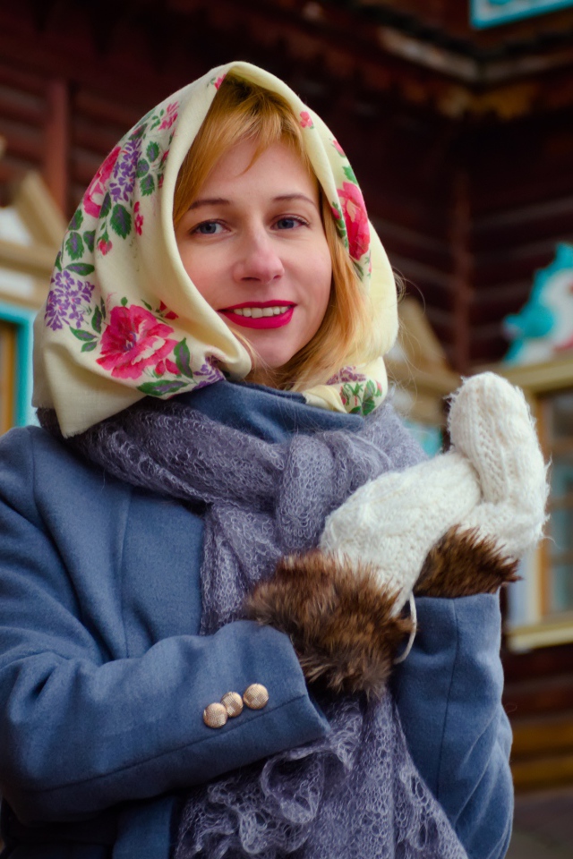 Красивая русская женщина в платке стоит у дома