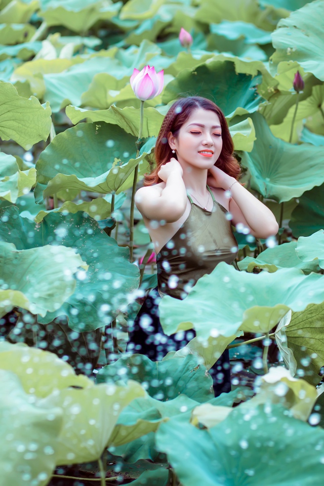 Красивая девушка азиатка в зеленых листьях лотоса 