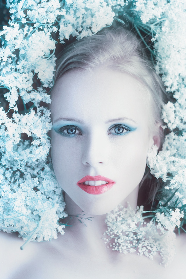 Красивая голубоглазая девушка на траве с белыми цветами