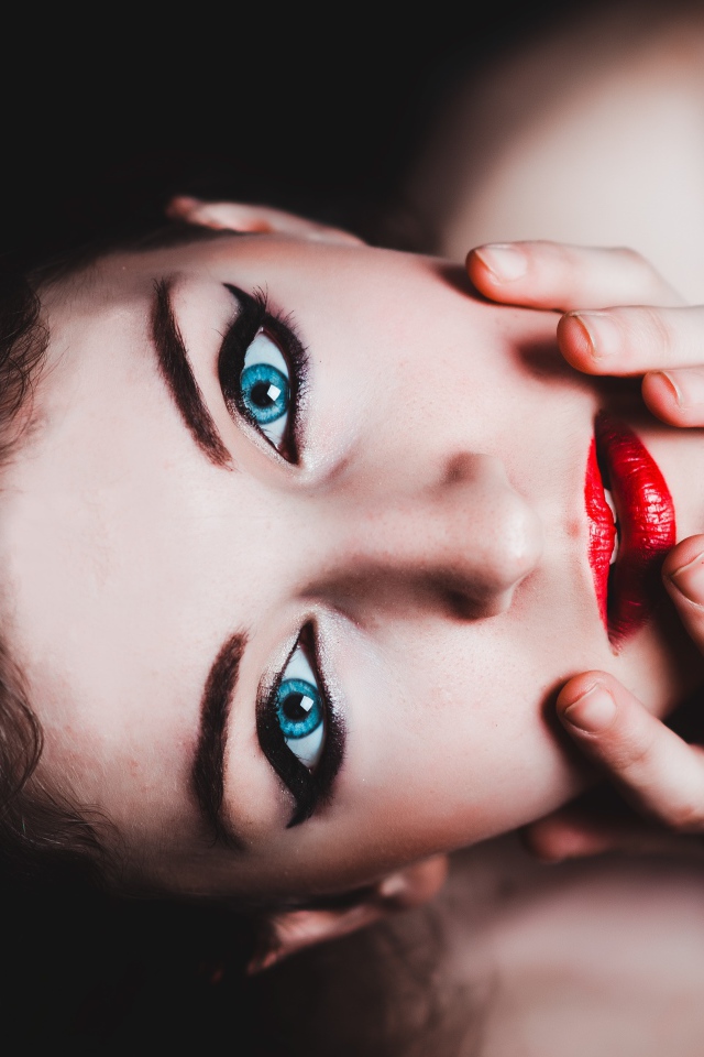 Красивая голубоглазая девушка с красными губами смотрит вверх 