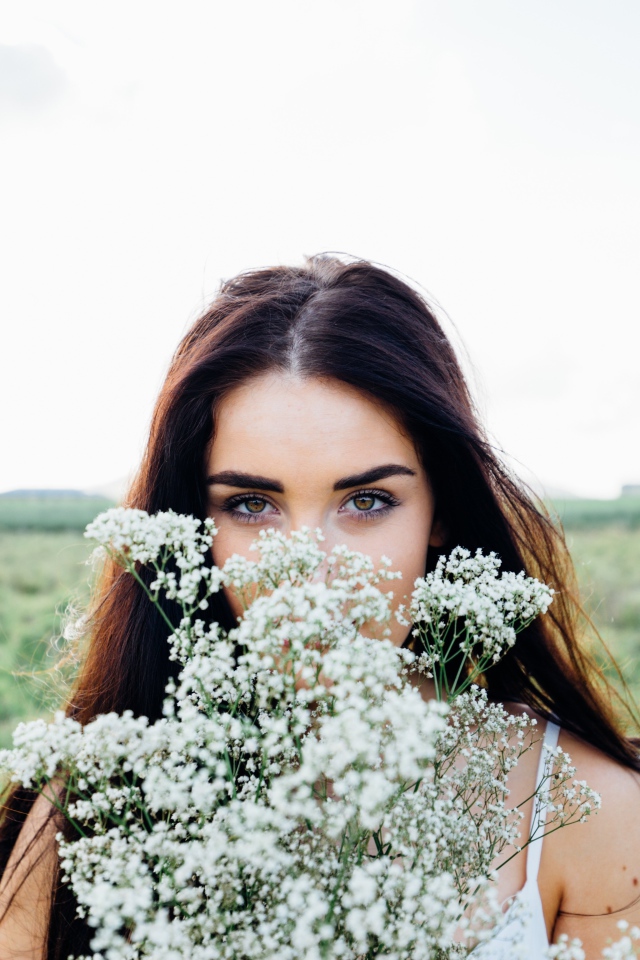 Красивая кареглазая девушка с букетом белых полевых цветов 