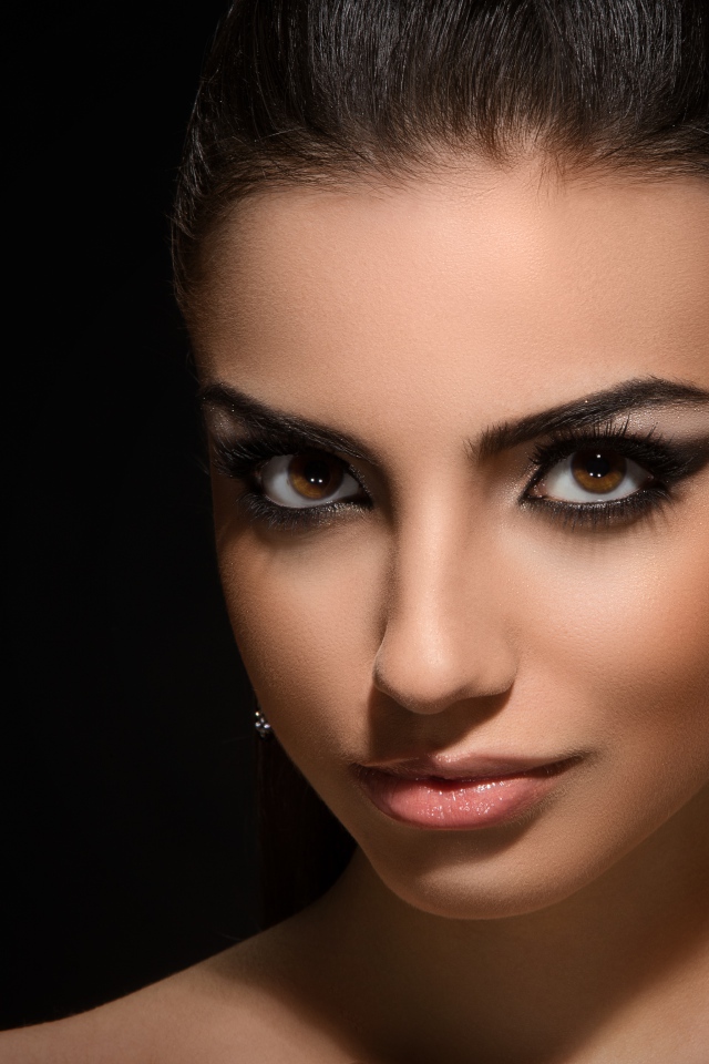 Красивая кареглазая девушка с прической на черном фоне