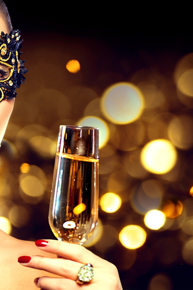 Красивая девушка в черной маске с бокалом шампанского