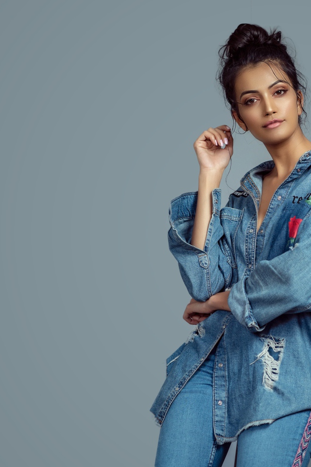 Красивая девушка в джинсовом костюме на сером фоне