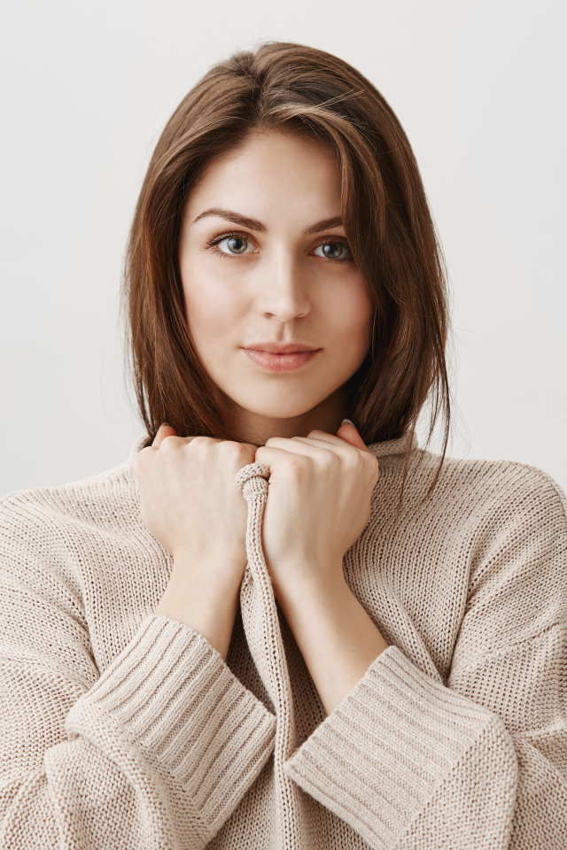 Красивая девушка в теплом свитере на сером фоне 