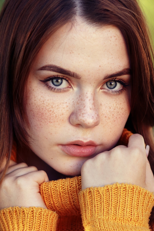 Красивая девушка в теплом свитере с веснушками на лице