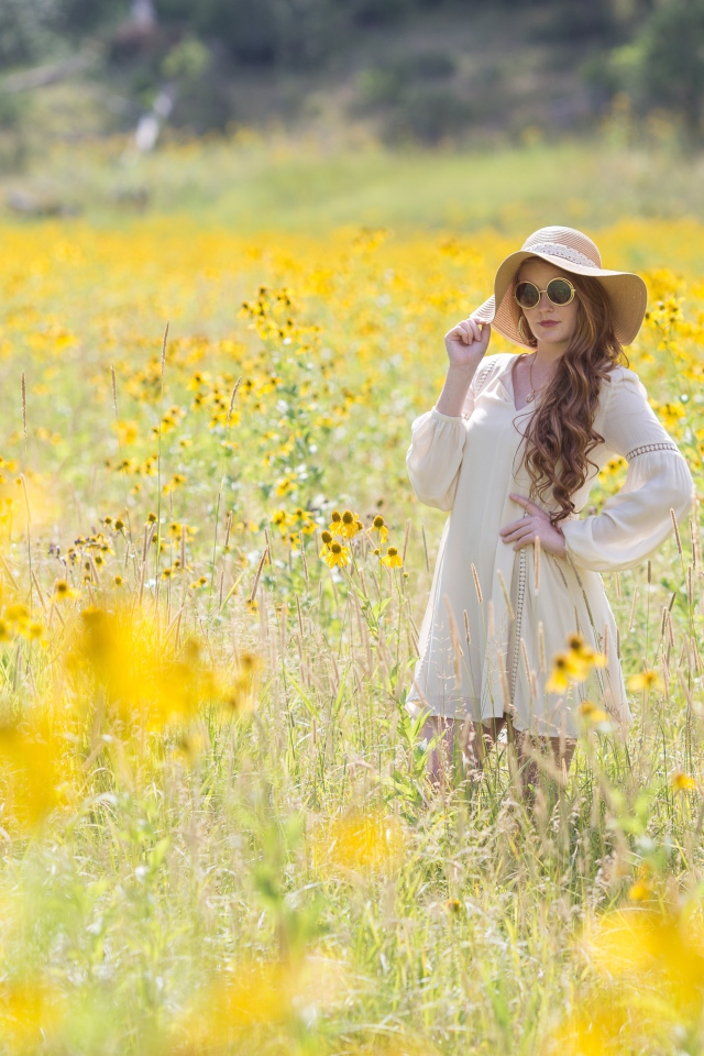 Красивая девушка в белом платье и шляпе на поле с желтыми цветами