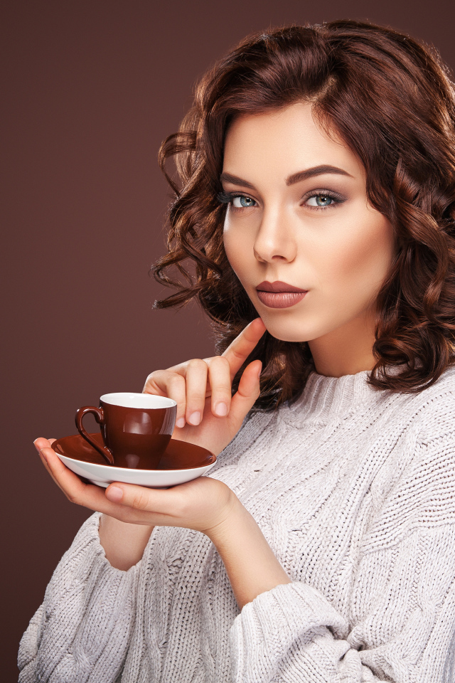 Красивая девушка в белом свитере с чашкой кофе
