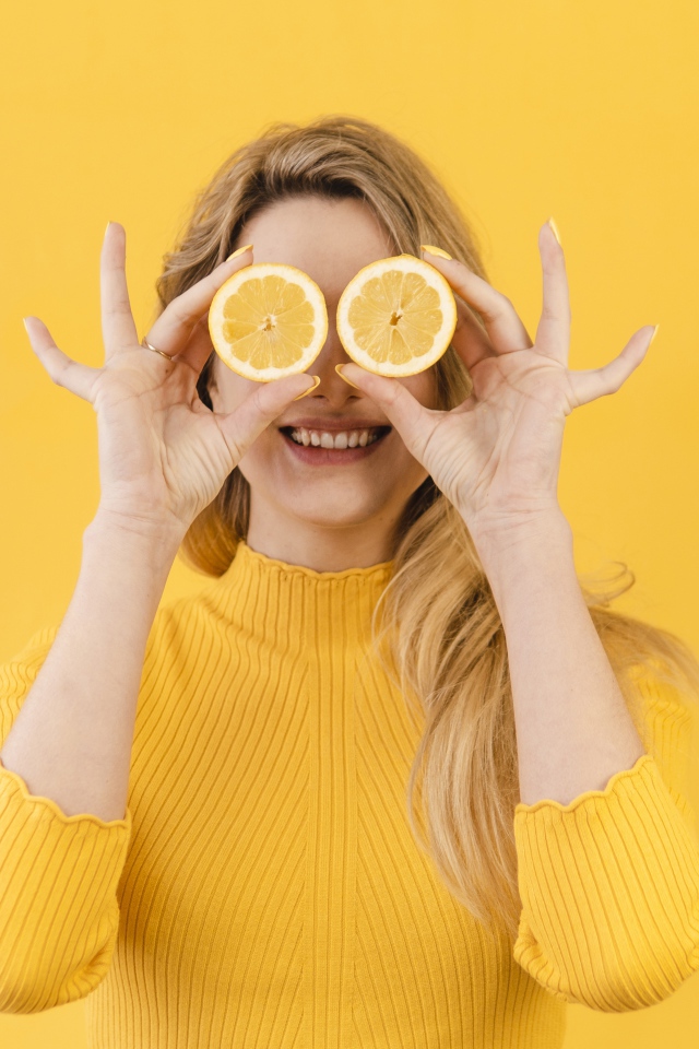 Красивая девушка в желтом свитере с лимоном