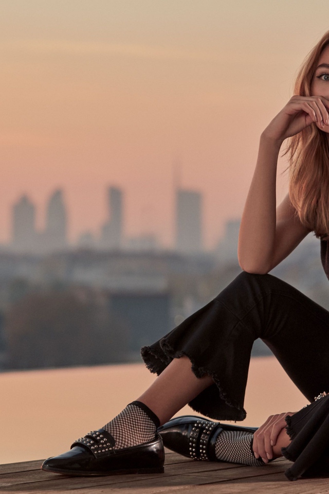 Красивая девушка в черном сидит  на мосту 