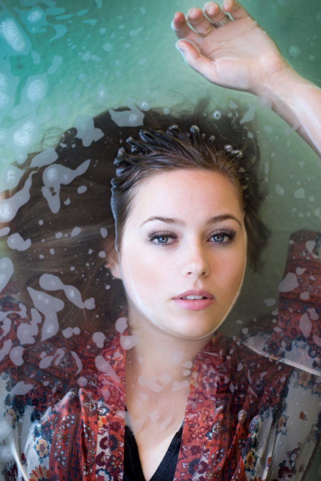 Красивая девушка лежит в одежде в воде 