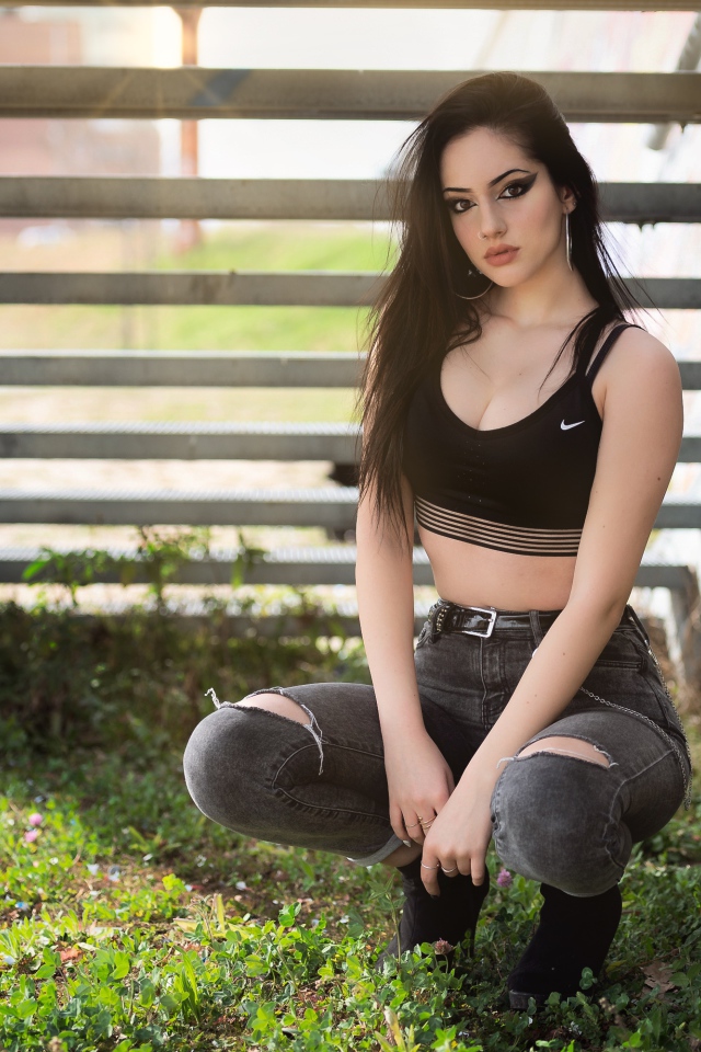 Красивая девушка сидит под лестницей 