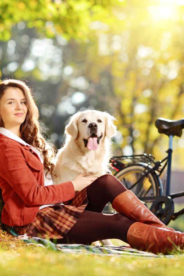 Красивая девушка сидит с собакой у дерева 