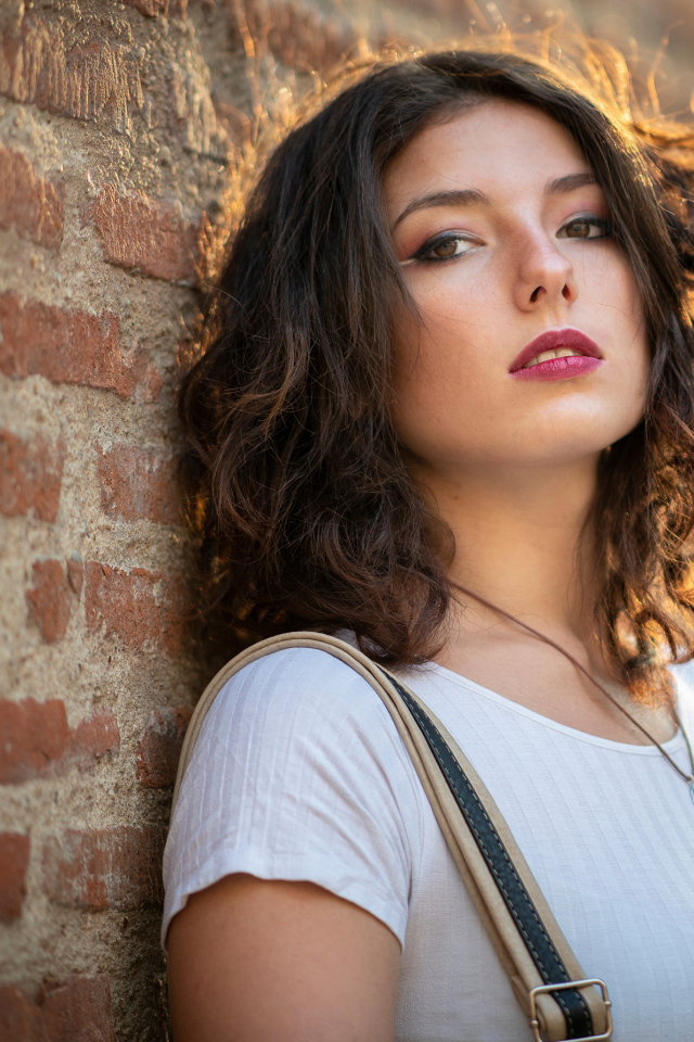 Красивая девушка стоит у стены 