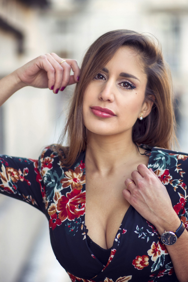 Красивая девушка с часами на руке стоит у стены