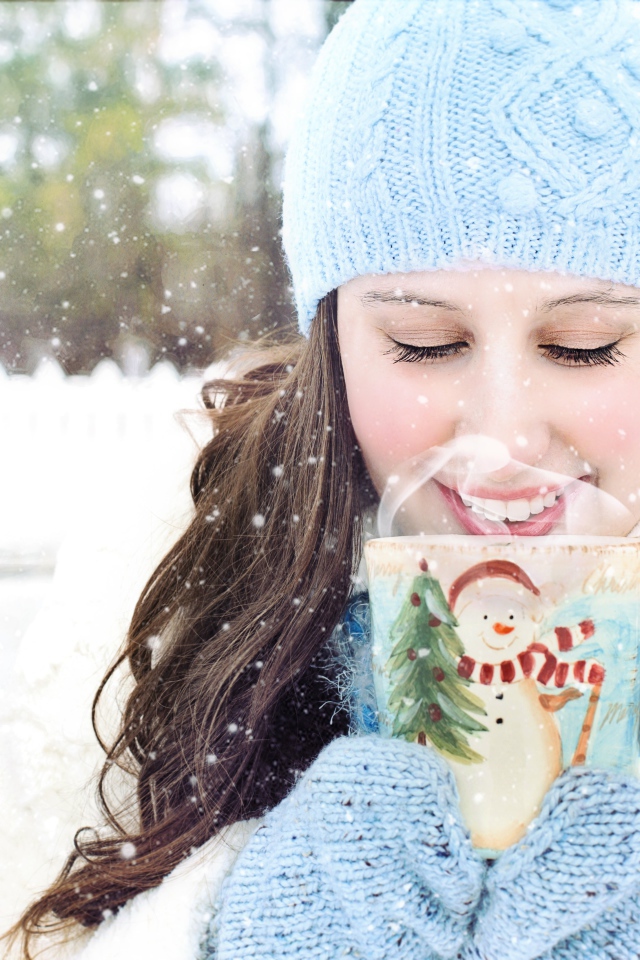 Красивая девушка с чашкой горячего кофе на улице зимой