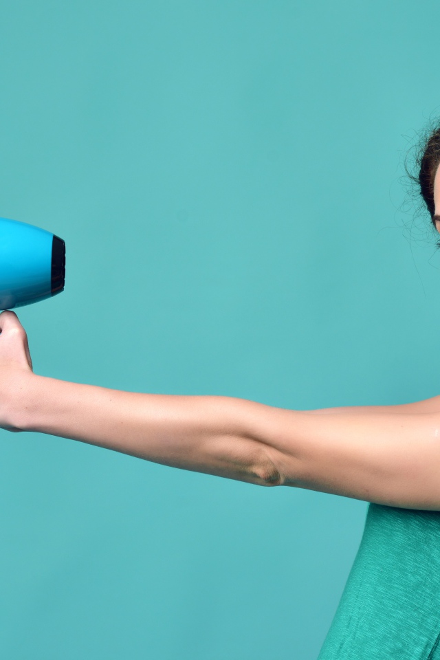 Красивая девушка с феном в руках на голубом фоне