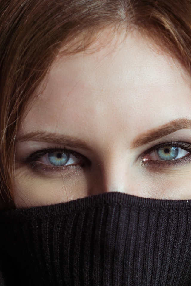 Красивая девушка с голубыми глазами закрыла лицо свитером 