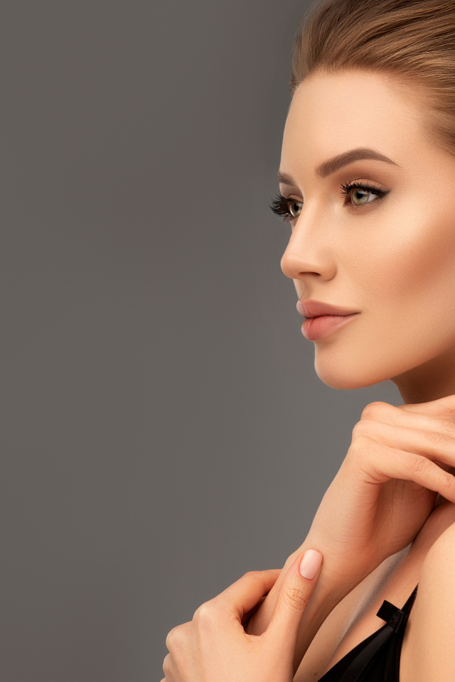 Красивая девушка с вечерней прической на сером фоне