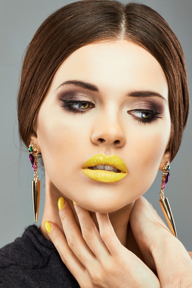 Красивая девушка с дорогими серьгами в ушах на сером фоне