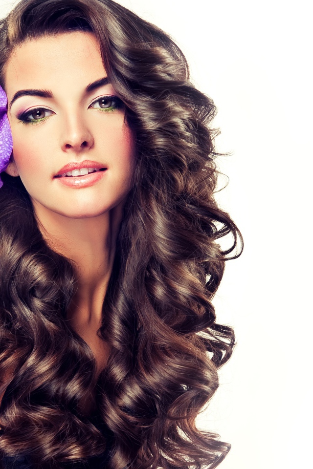 Красивая длинноволосая девушка с цветком в волосах на белом фоне