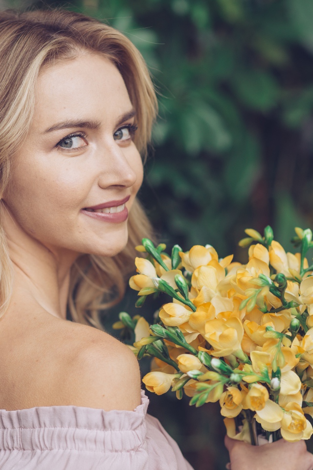 Красивая улыбающаяся девушка с букетом желтых цветов в руке 
