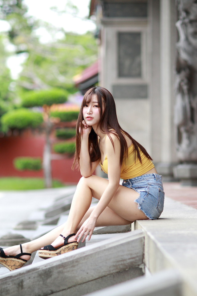 Красивая молодая девушка азиатка сидит на ступеньках 