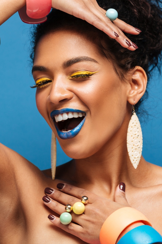 Красивая молодая девушка с ярким разноцветным макияжем на голубом фоне