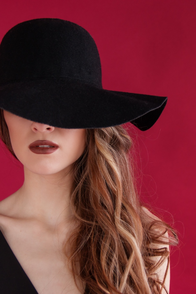 Большая черная шляпа закрывает лицо девушки