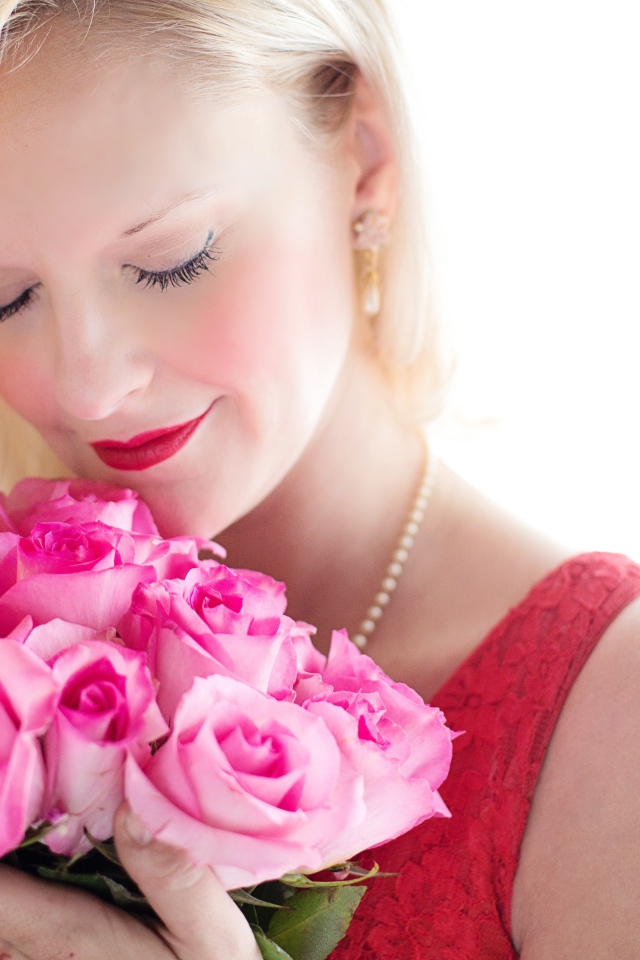 Блондинка с закрытыми глазами нюхает букет роз