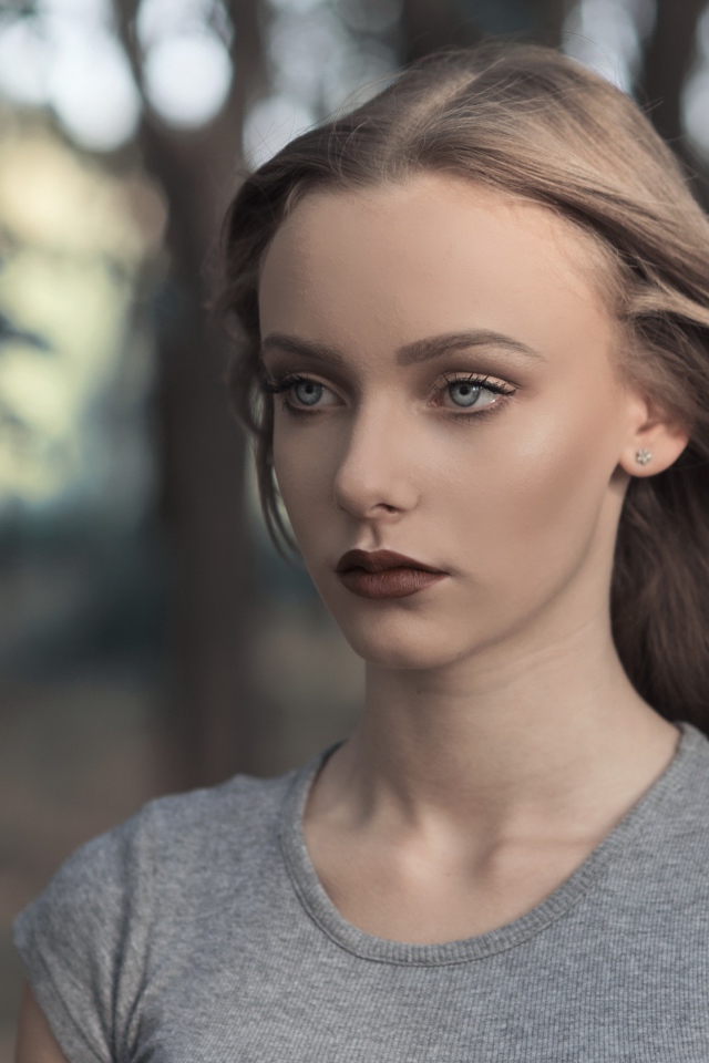 Голубоглазая девушка в серой майке в парке 