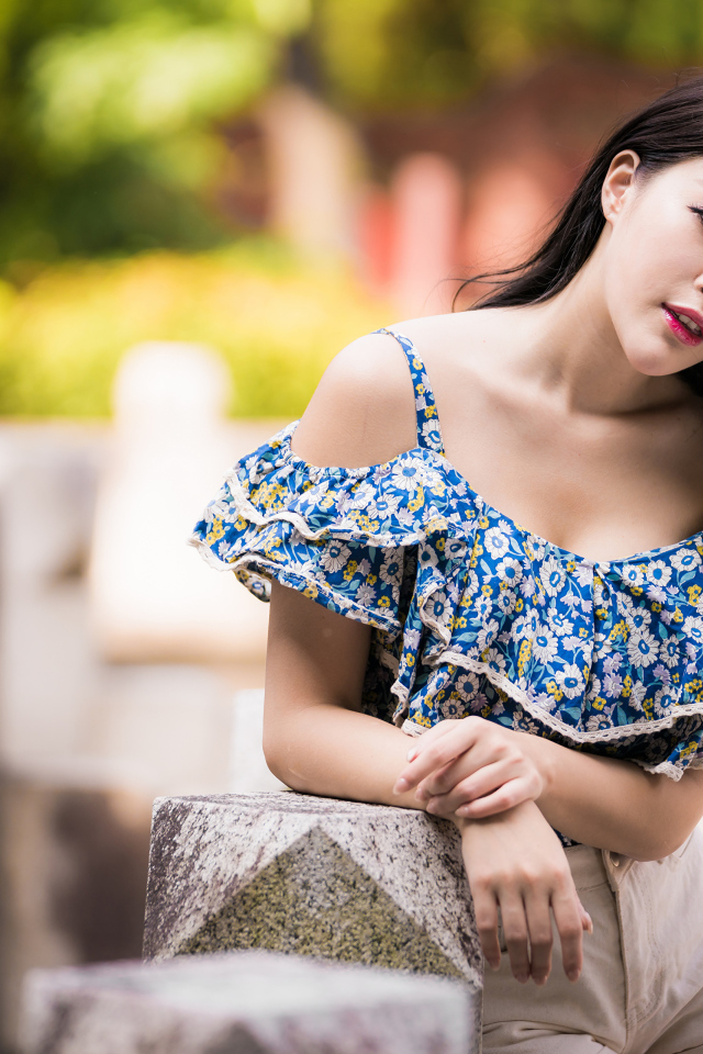 Кареглазая азиатка в яркой кофте в парке 