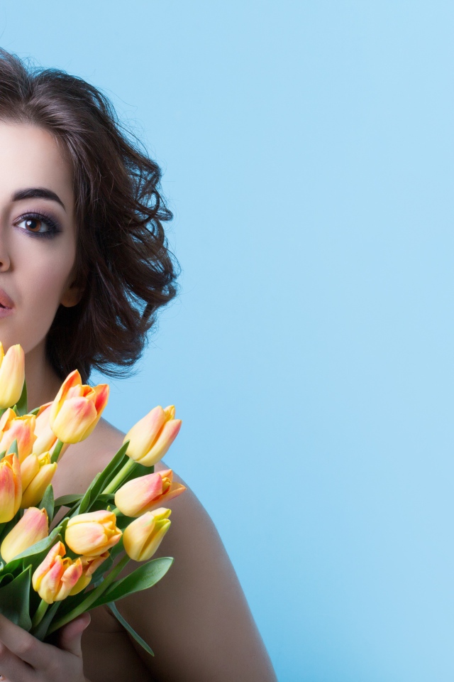 Кареглазая шатенка с букетом тюльпанов на голубом фоне