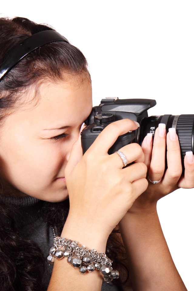 Молодая девушка шатенка с фотоаппаратом в руках на белом фоне