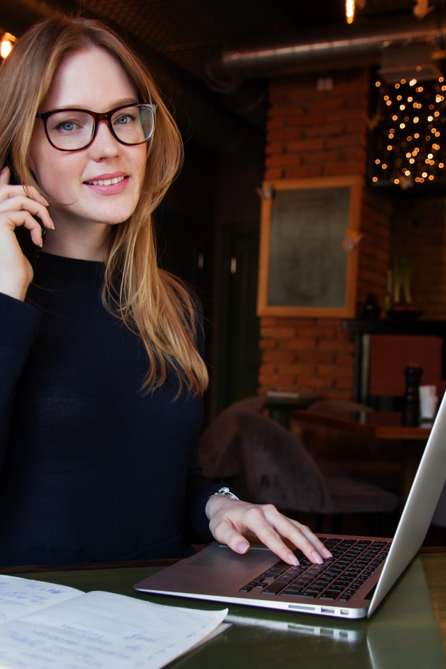 Деловая девушка в очках сидит с кафе с ноутбуком