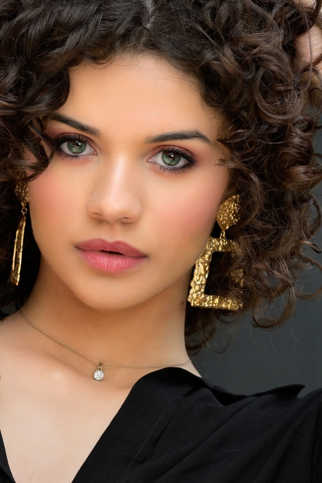 Кудрявая девушка с рукой в волосах в черной рубашке 