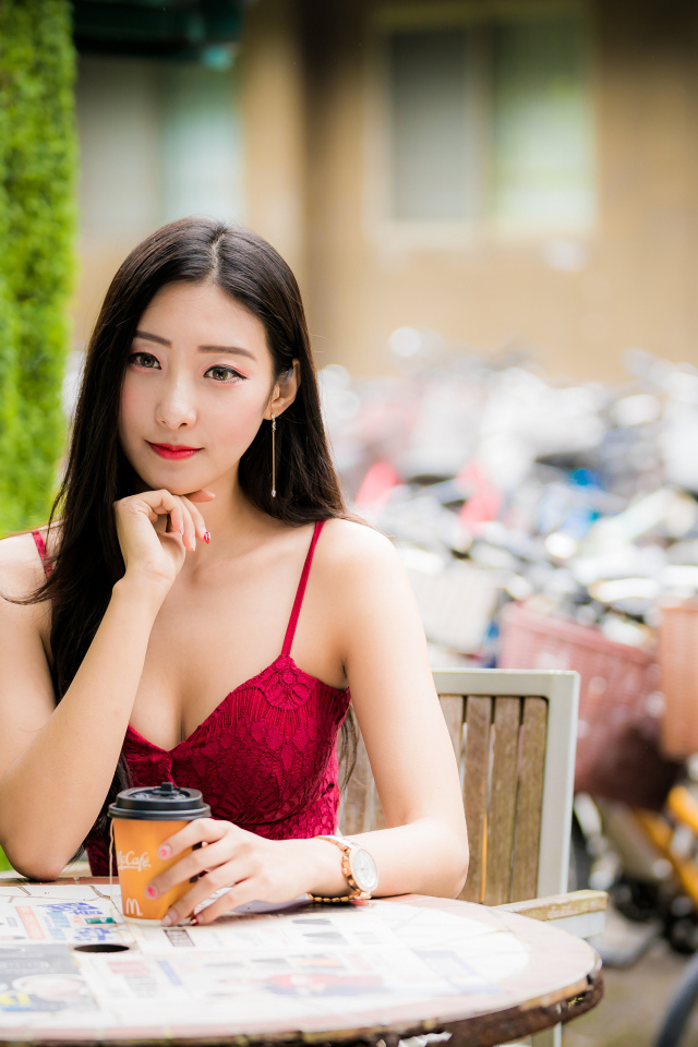 Милая девушка азиатка сидит за столиком в кафе
