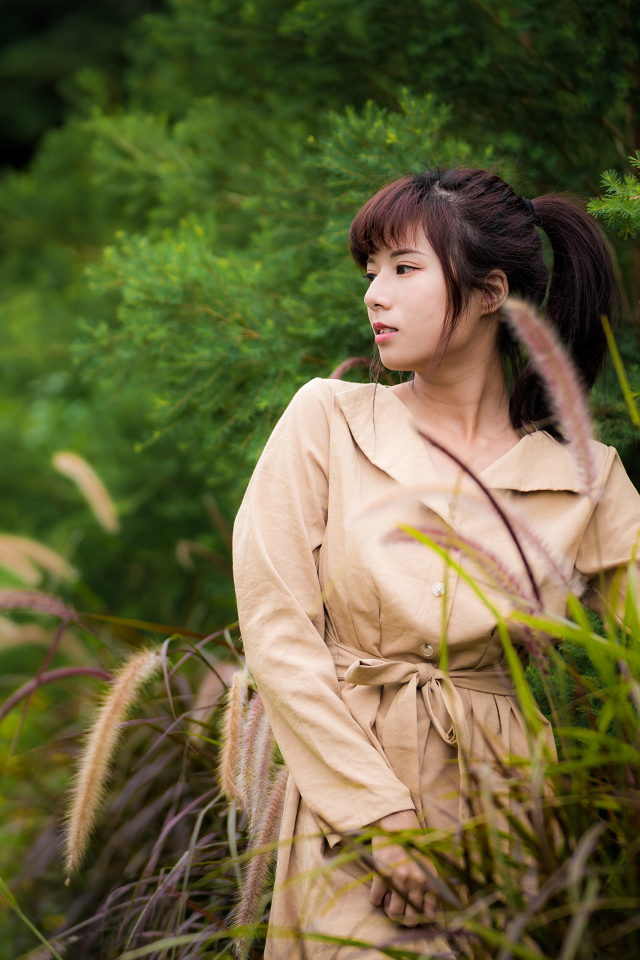 Милая азиатка в пальто в парке 