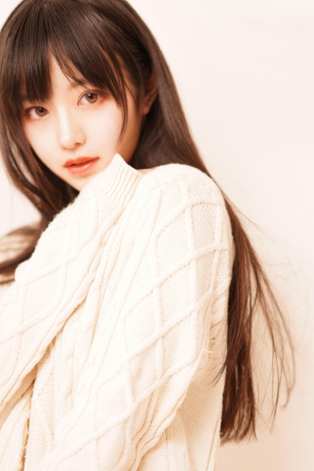 Милая азиатка в белом свитере на розовом фоне