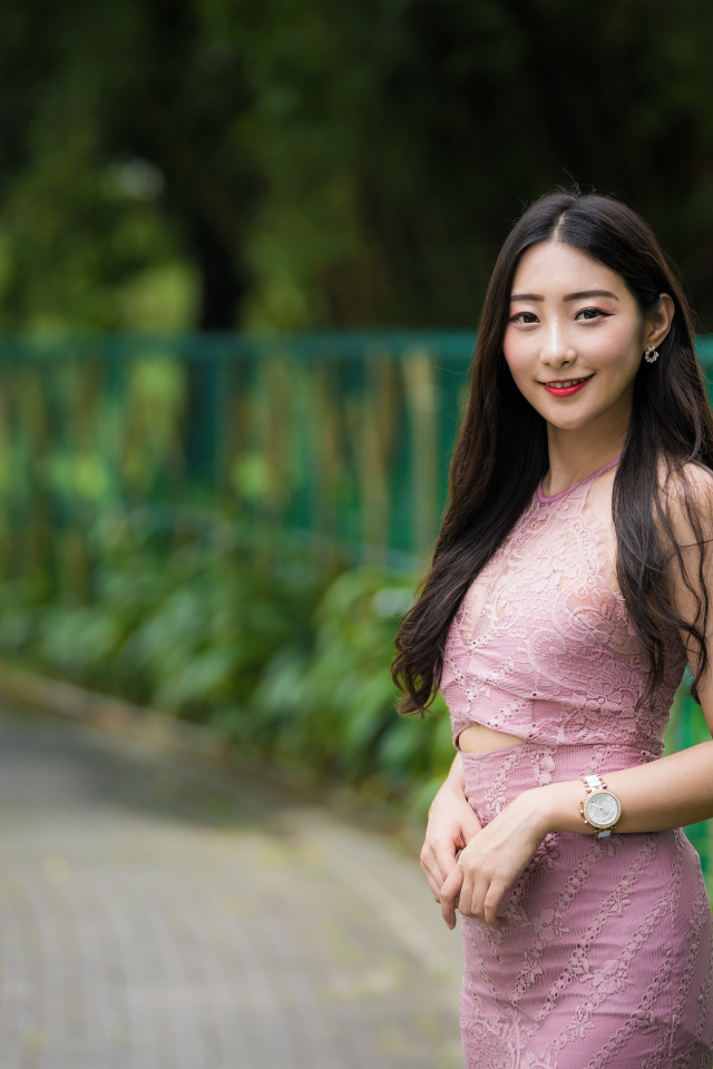 Милая улыбающаяся азиатка в костюме у забора